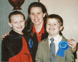 Photo of teacher with 2 students wearing their Ribbon of Achievement Awards at the Recital